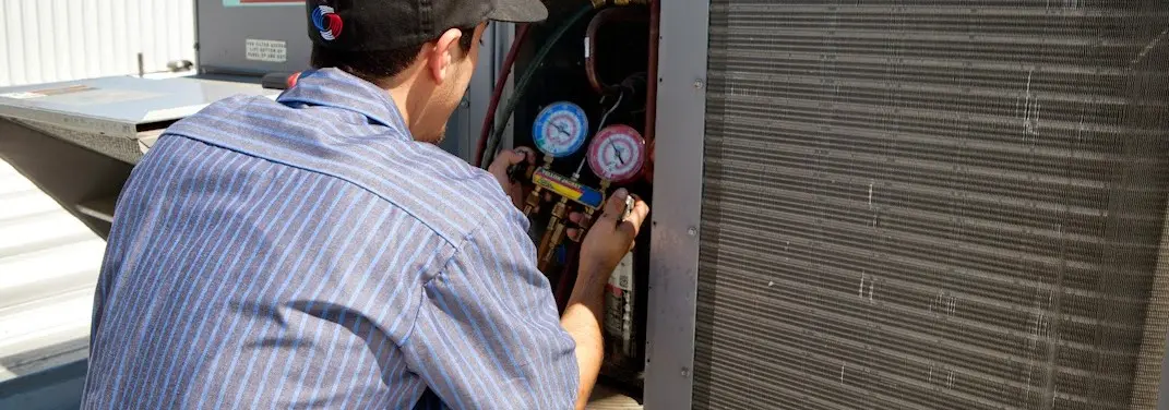 HVAC technician servicing a condenser unit in Pelham